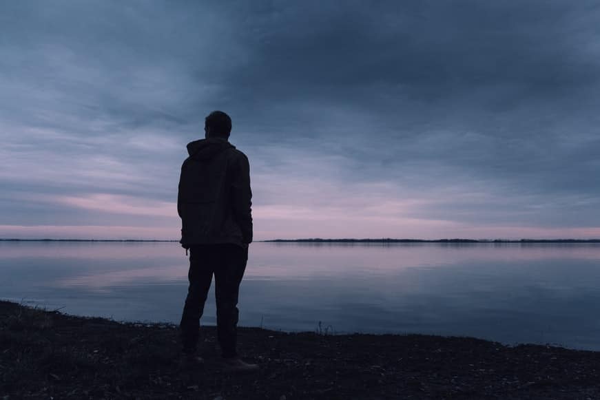 A silhouette of a lone man standing on a beach.