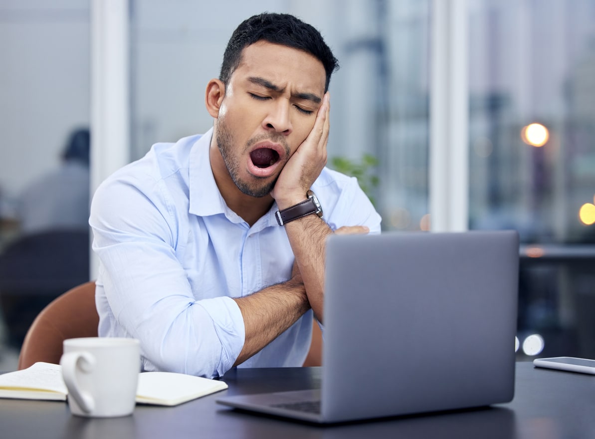 Young businessman yawning at his desk.