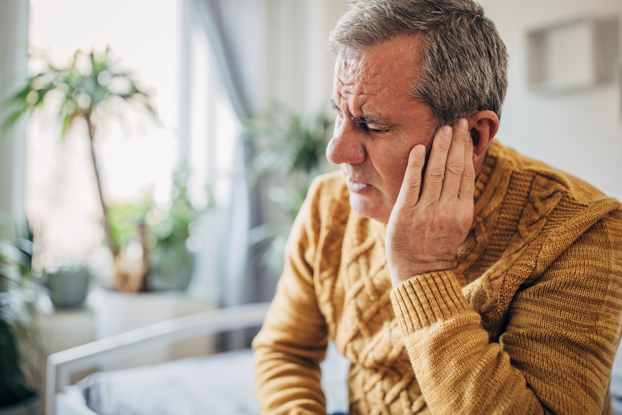 Man holding his ear, experiencing ear pain.