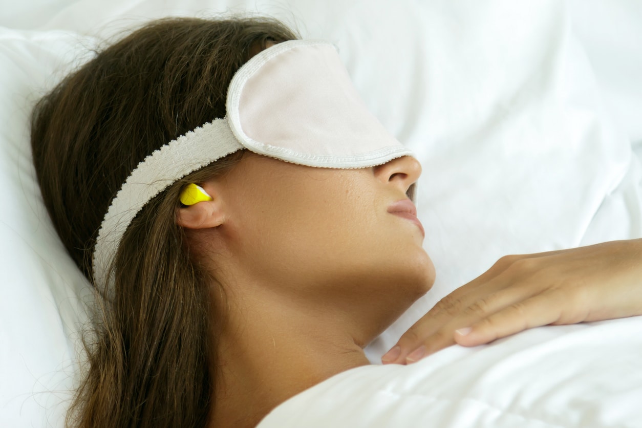 Woman sleeping with earplugs and an eye mask.