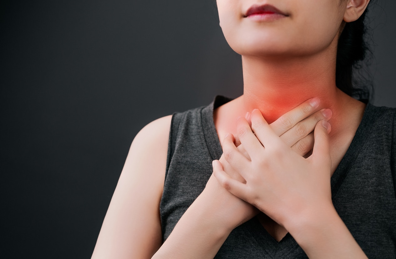 Woman holding her red, sore throat.