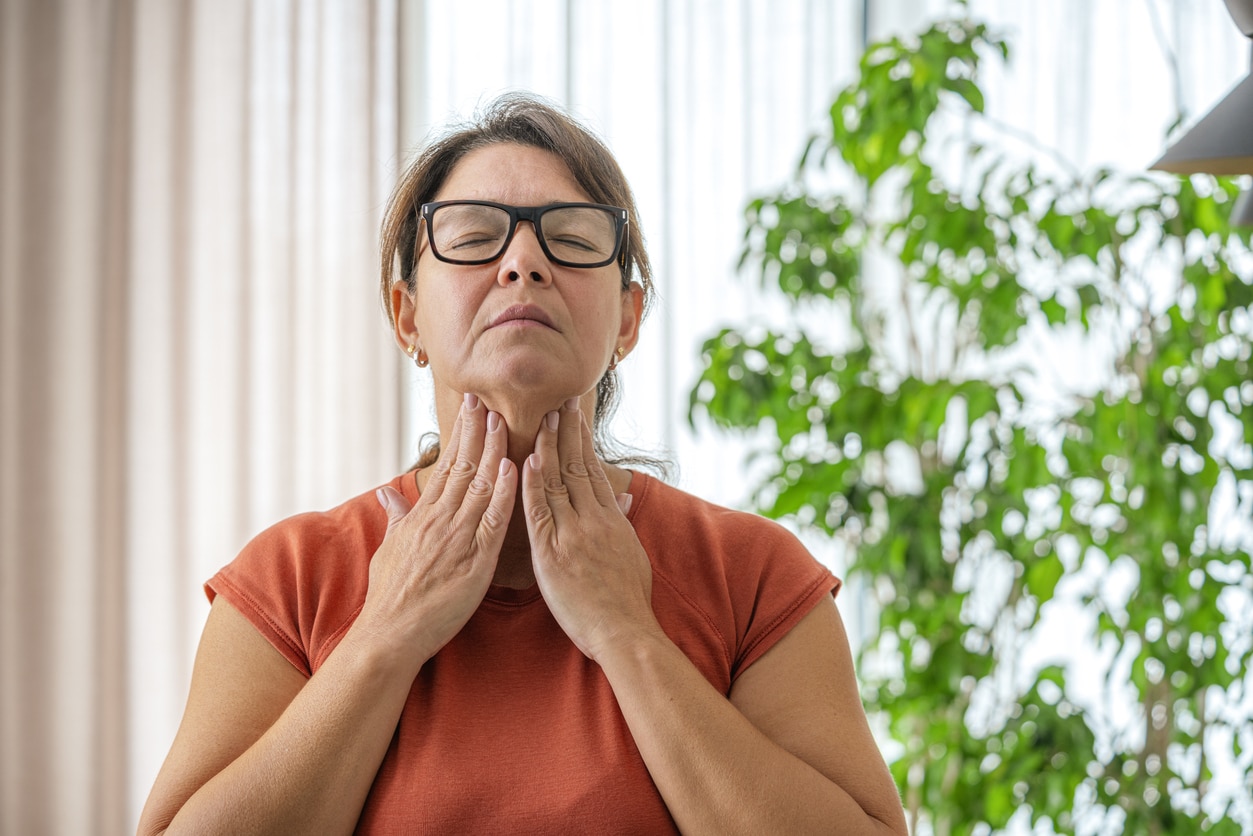 Woman touching her sore throat with both hands