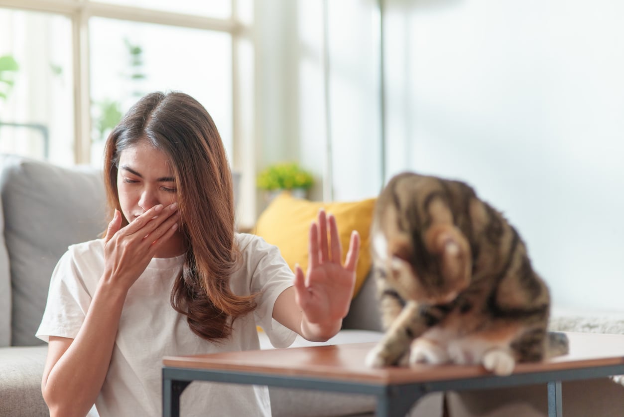 Woman with allergies putting a hand up to her cat