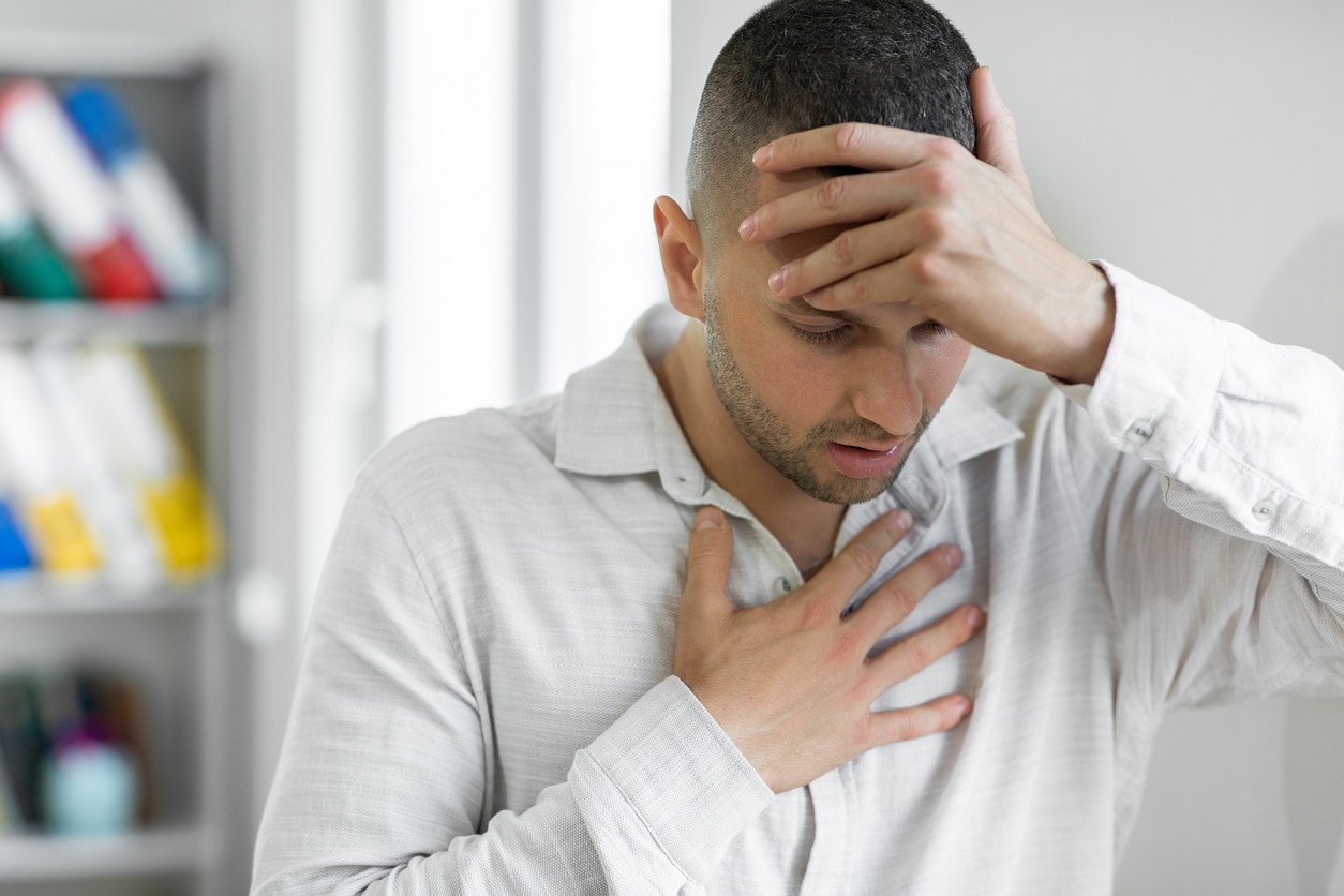 Man with anaphylaxis holding his forehead and chest