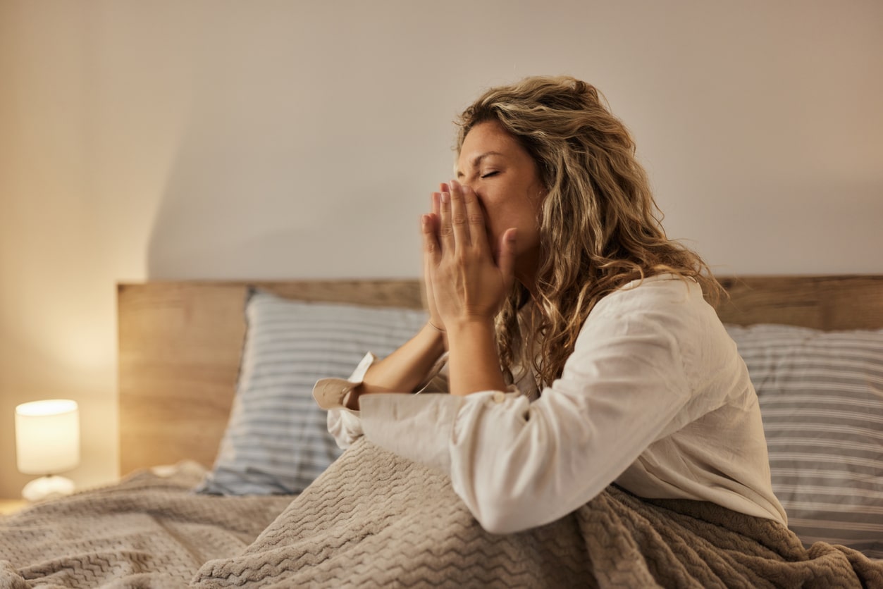 Woman sneezing in bed