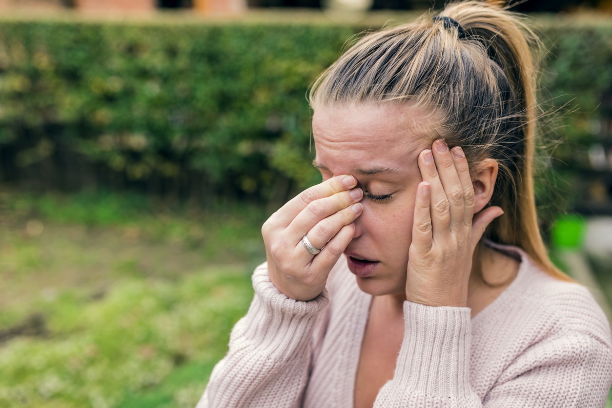 Woman with severe allergies holding her nose and head