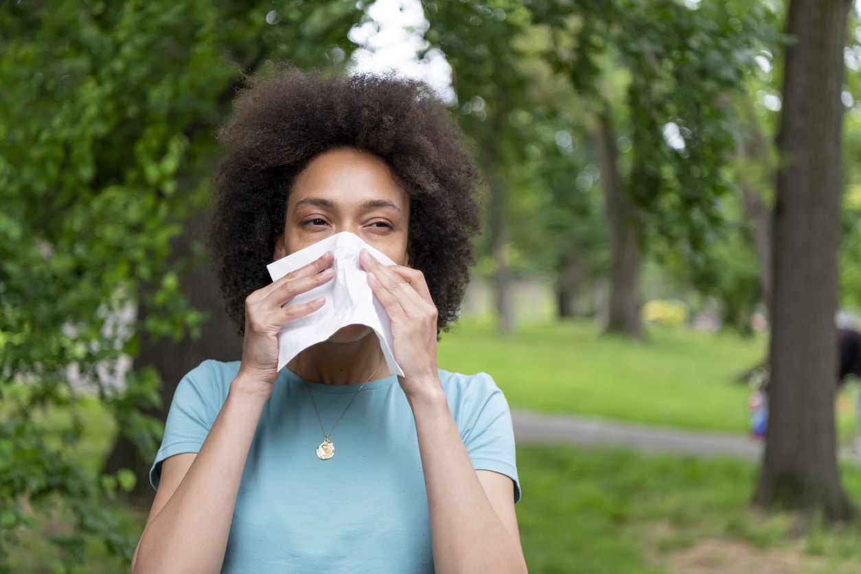 Woman with environmental allergies sneezing into a tissue