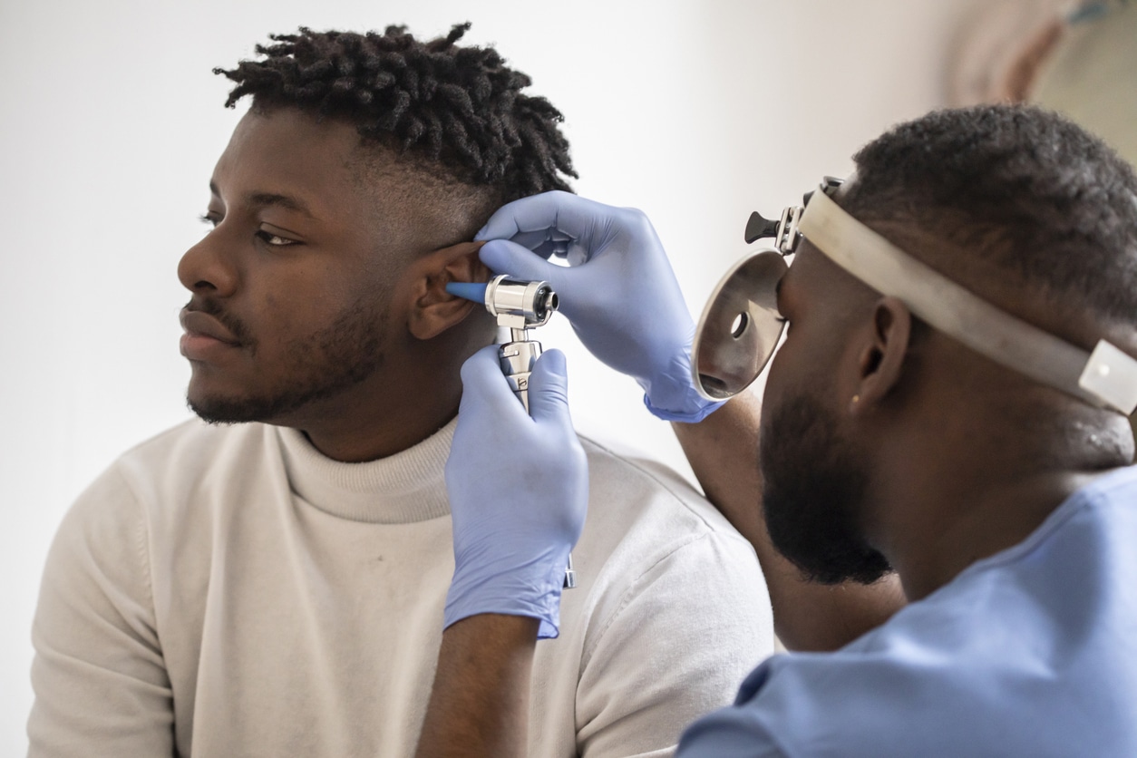 ENT specialist conducting an ear exam on a young man